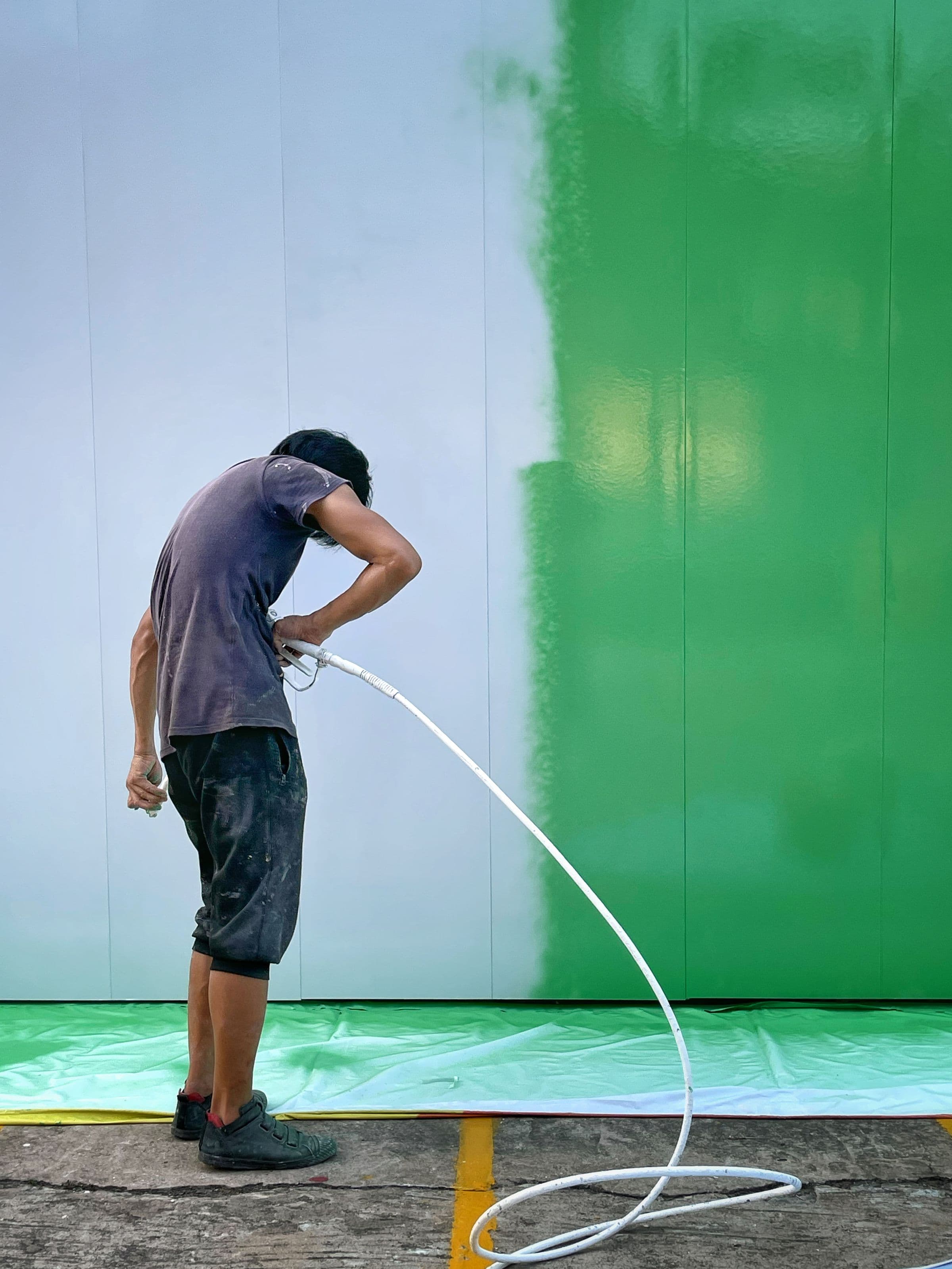 Painter spray-coating a large commercial wall
